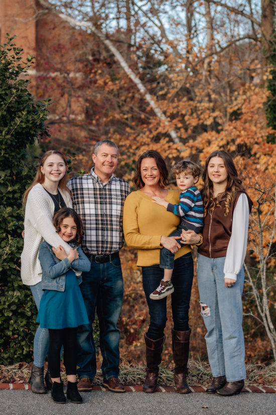 Family standing in front of fall foliage